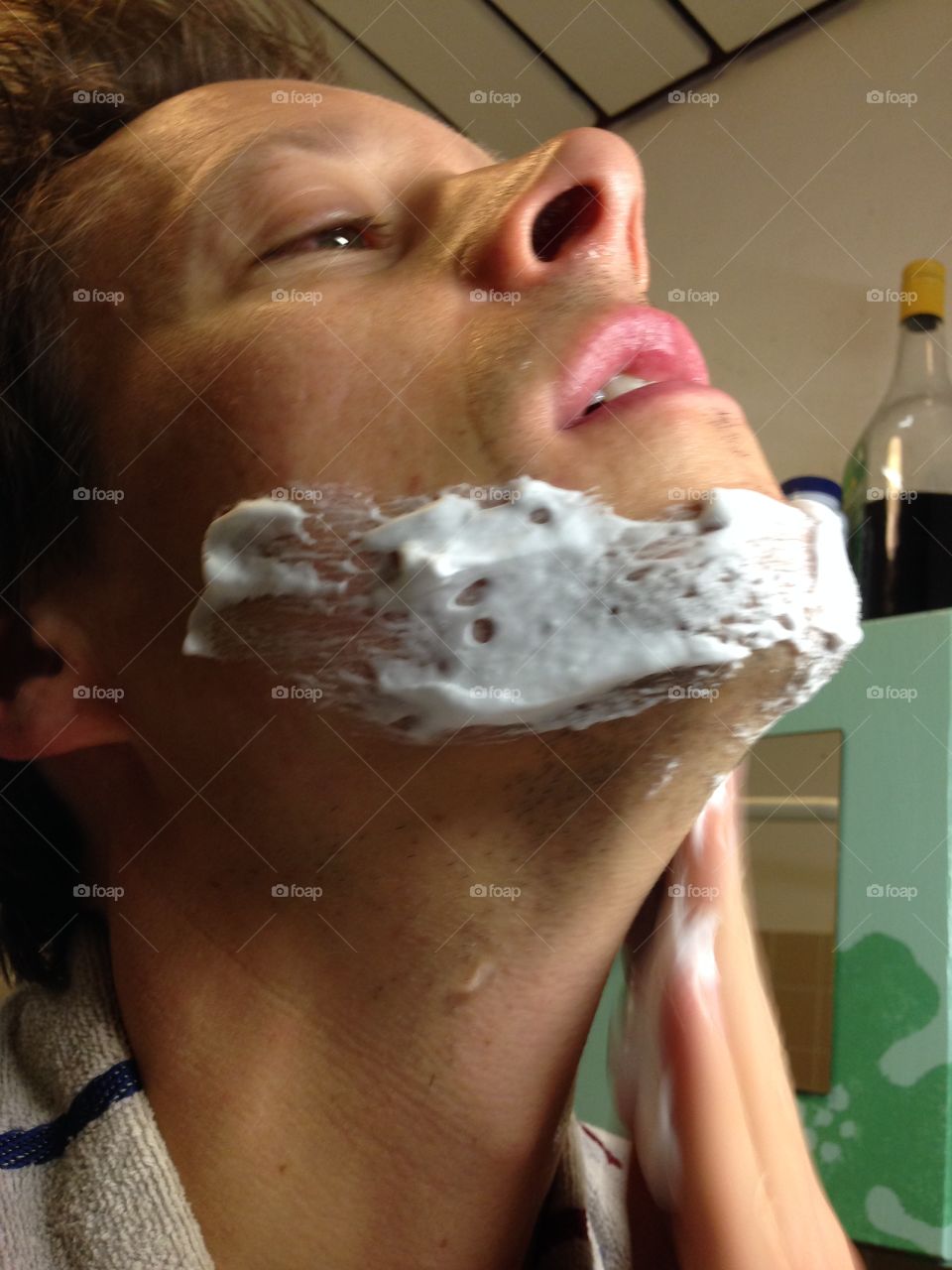 Man applying shaving foam on his face to prepare for shaving.