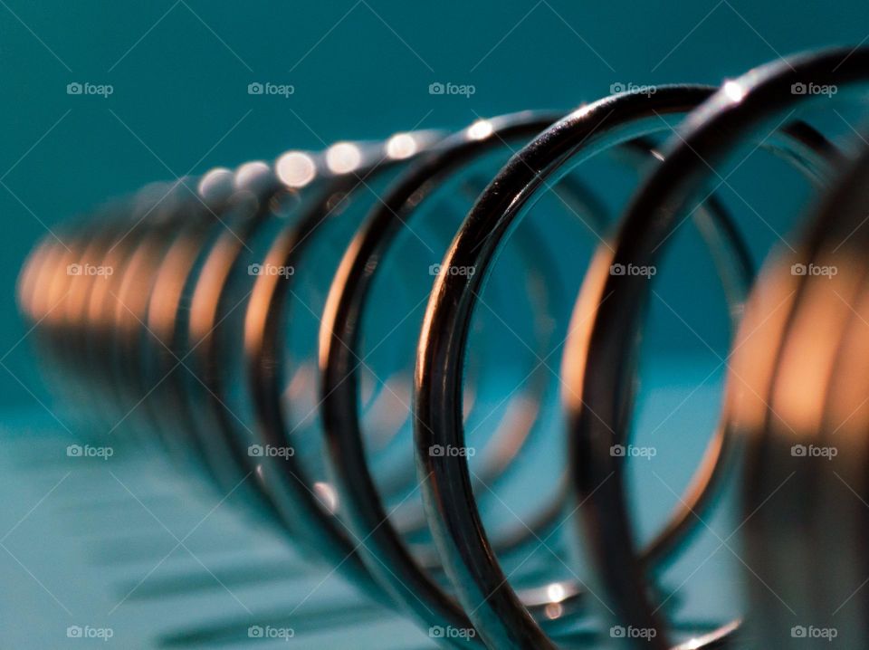 Metal spiral on a blue background with warm light reflection.