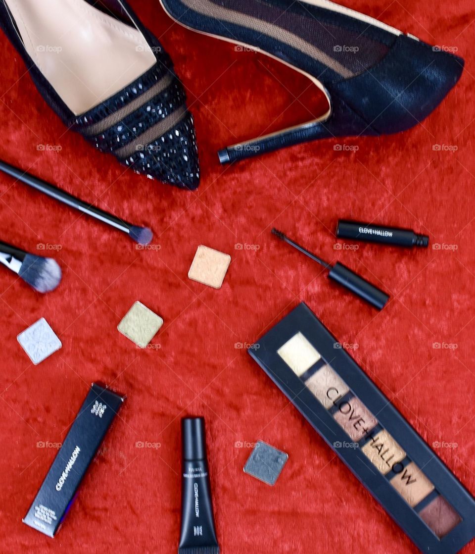 Still life flat lay with black dress heels and makeup 