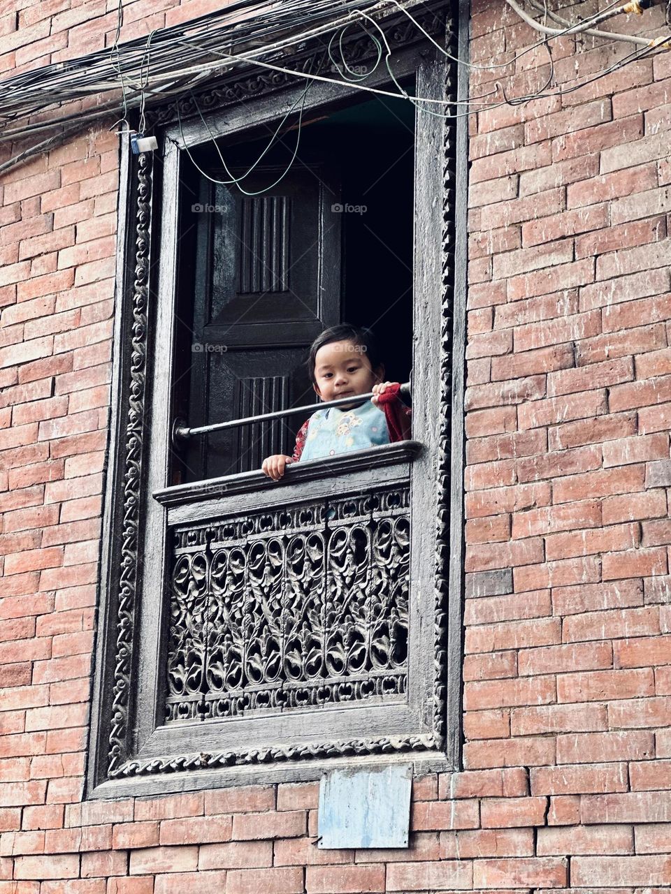 Curious kid looking outside the window in Kathmandu, Nepal