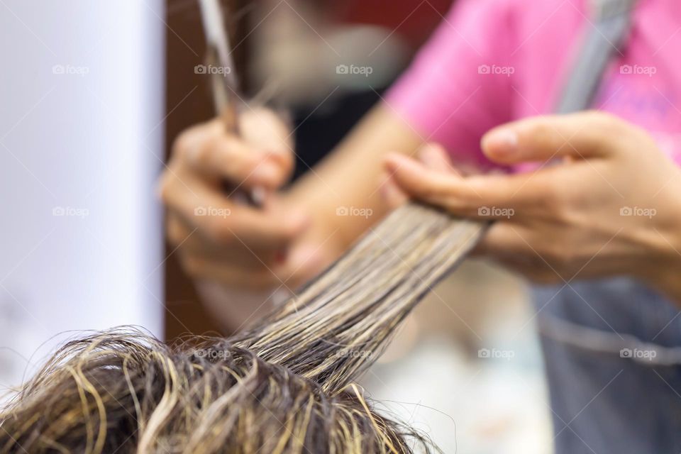 Hairdresser cutting the hair, beauty care concept. Closeup on hands with scissors.