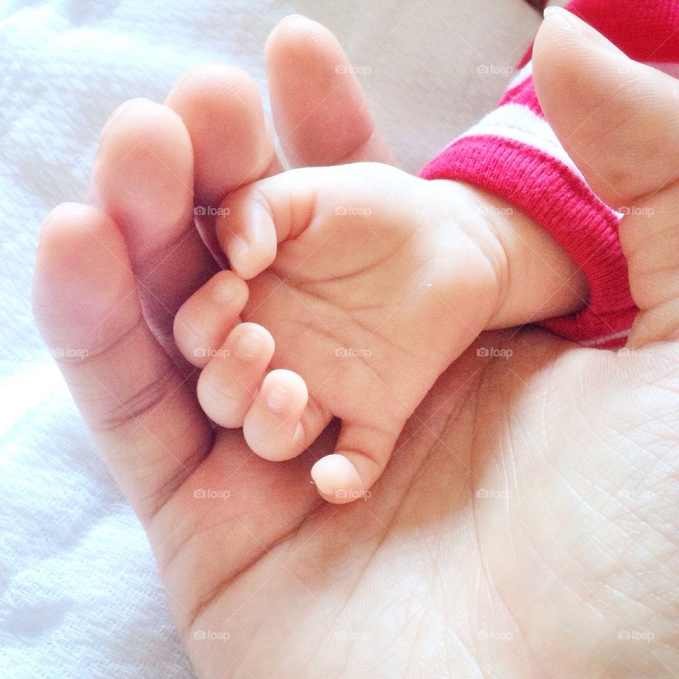Mother's hand holding babies hand