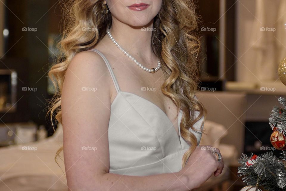 Beautiful girl in a white elegant dress and a pearl necklace