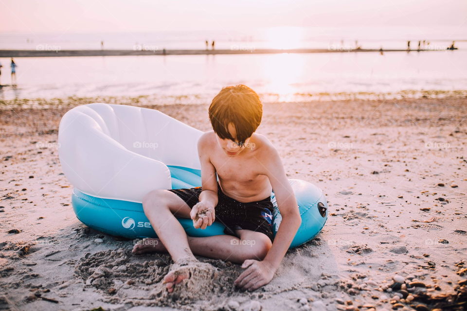 Young boy playing with sand on the beach 