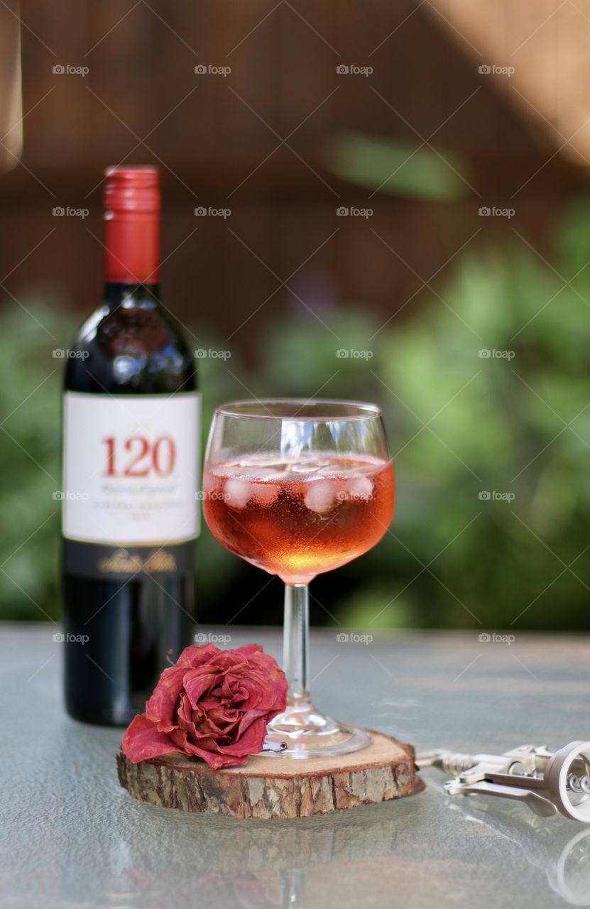 Closeup of red cocktail in wine glass with wine bottle 