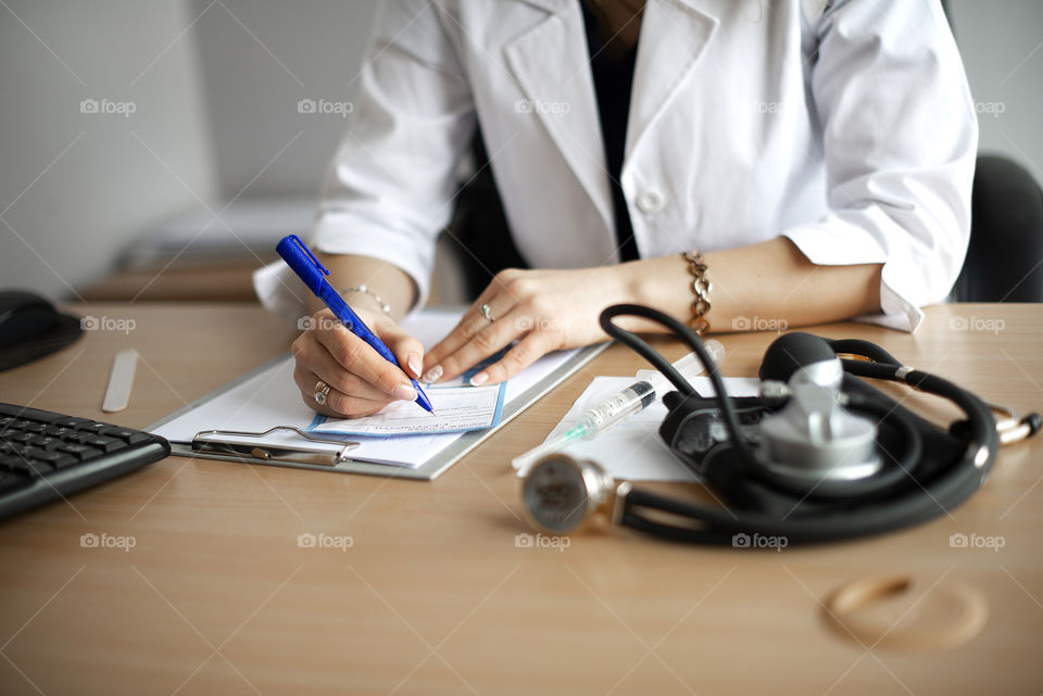 Close up of female doctor writing prescription paper