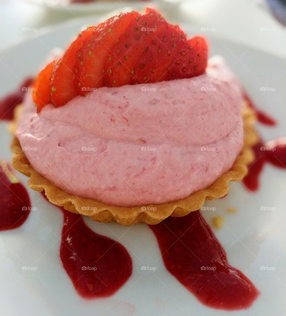 Dessert with strawberries, pudding, cake and red sauce