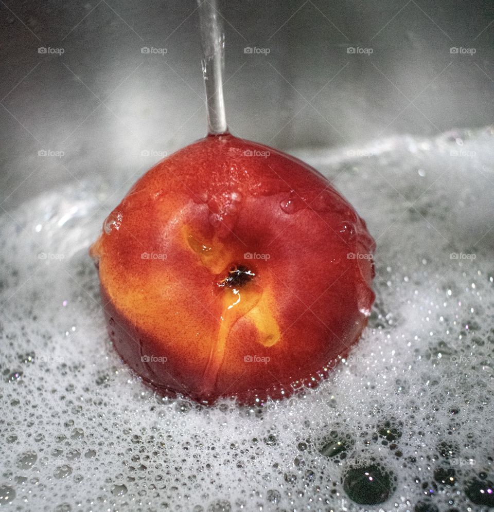 Delicious orange nectarine fruit being cleaned in soap and water