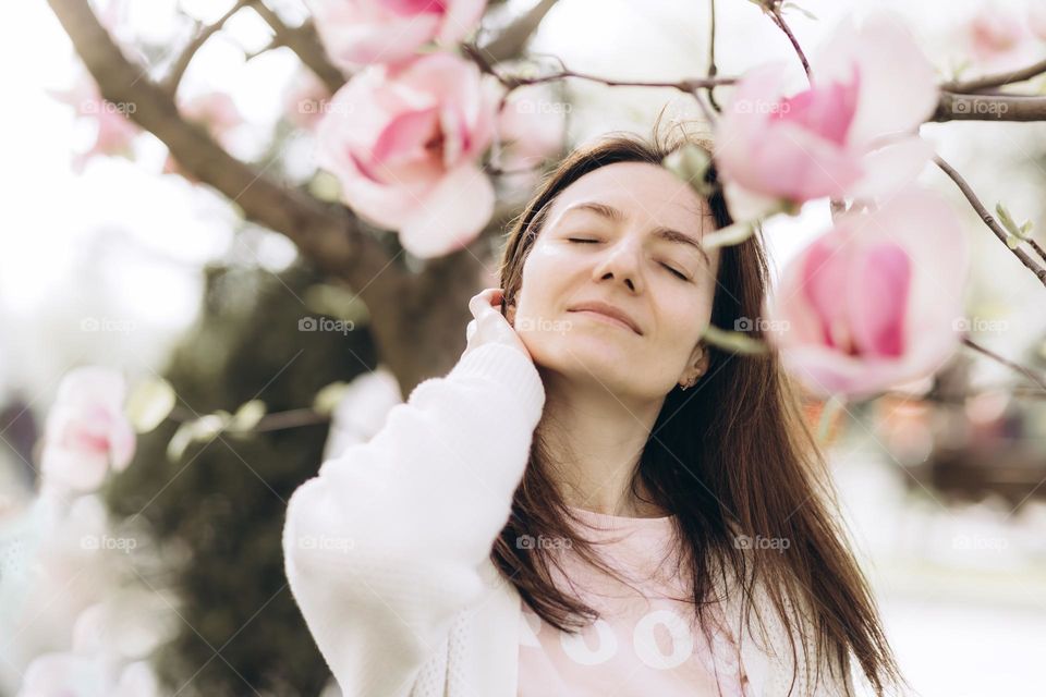 Portrait of woman with magnolia flowers in foreground.