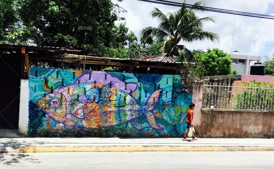 Child passes vibrant street art in Tulum, Mexico