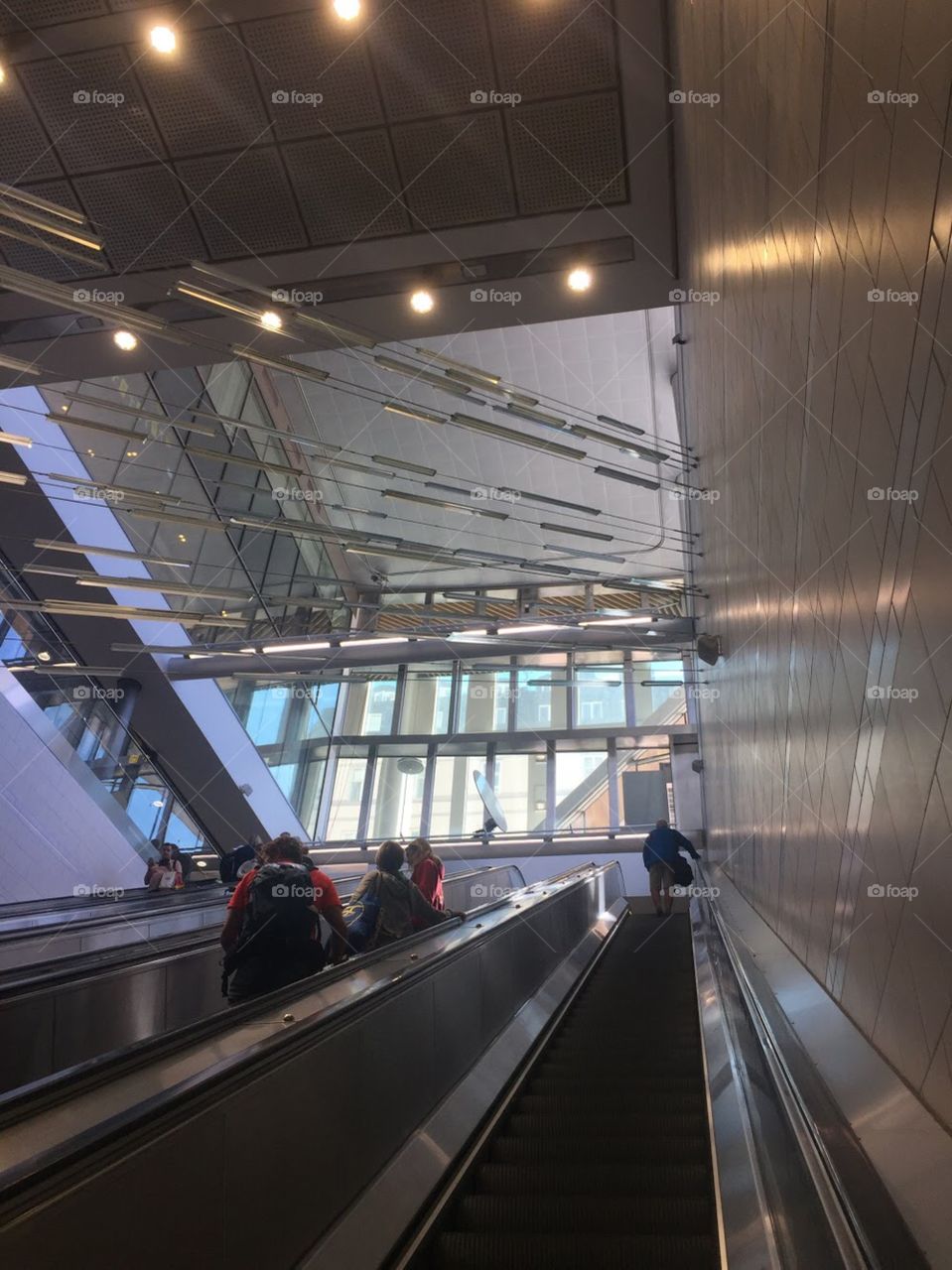A modern escalator with an installation of silver, gleaming lights shooting across the space like stars. 