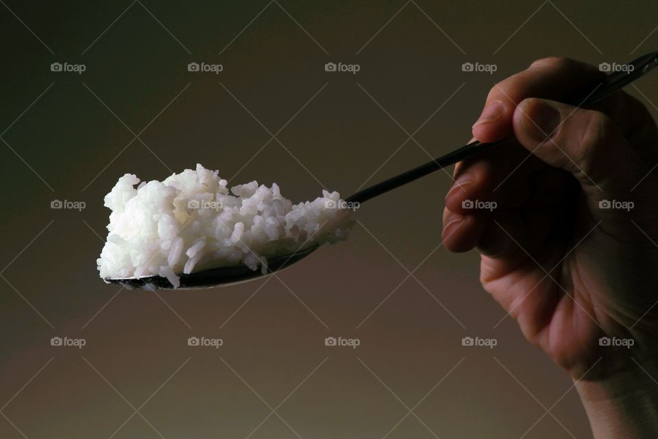 hand holding a spoonful of cooked rice