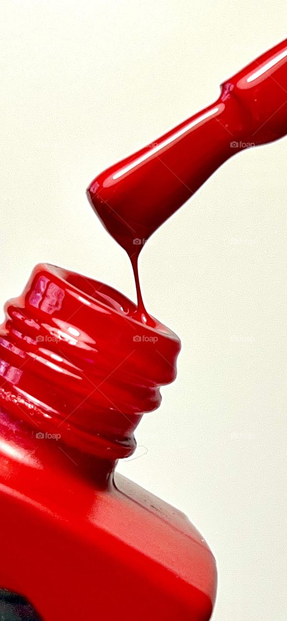 Bright red classic nail polish color. Shot close up on a white background