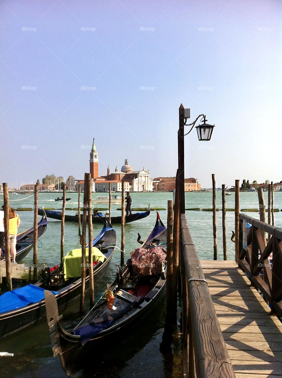 View of gondolas in Venice with pastel colored sky and turquoise water.