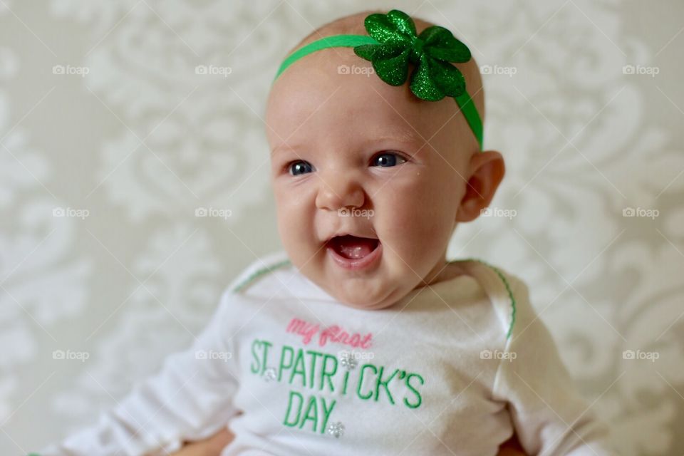 Baby's first St. Patrick's Day - cute little smiling newborn girl wearing shamrock headband and green tutu