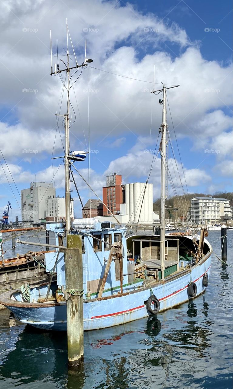 Fischerboot im Hafen bei leicht bewölktem Himmel / Fishing boat in harbor under light cloudy sky