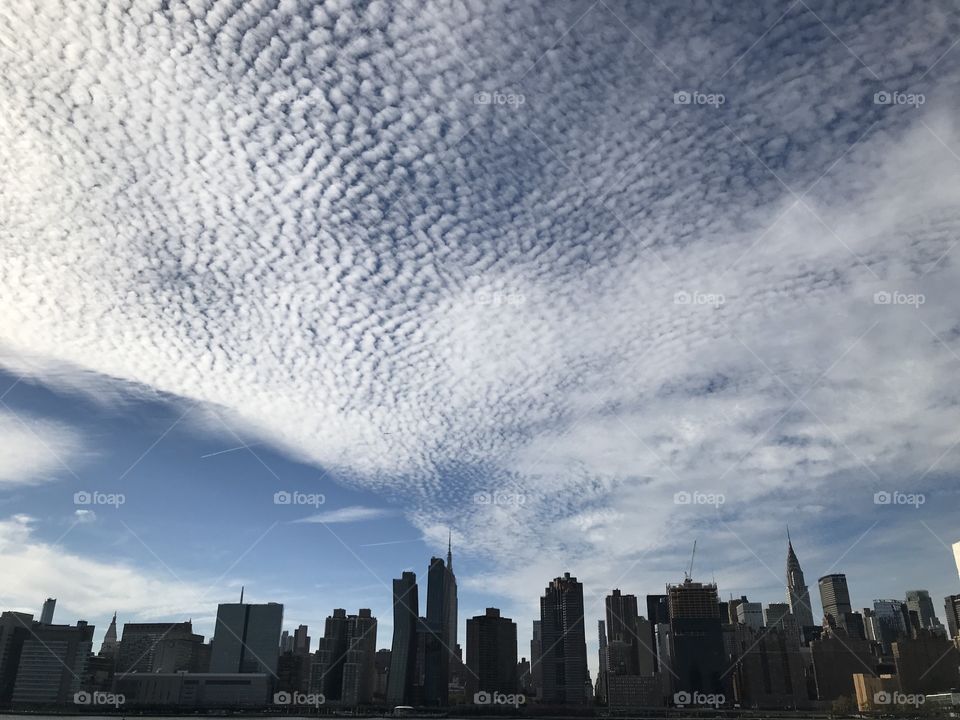 View of Manhattan skyline from east river ferry with clouds