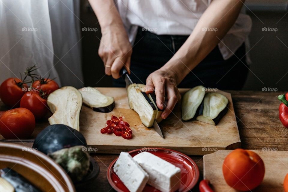 Woman cooking a healthy meal, using vegetables and feta cheese.