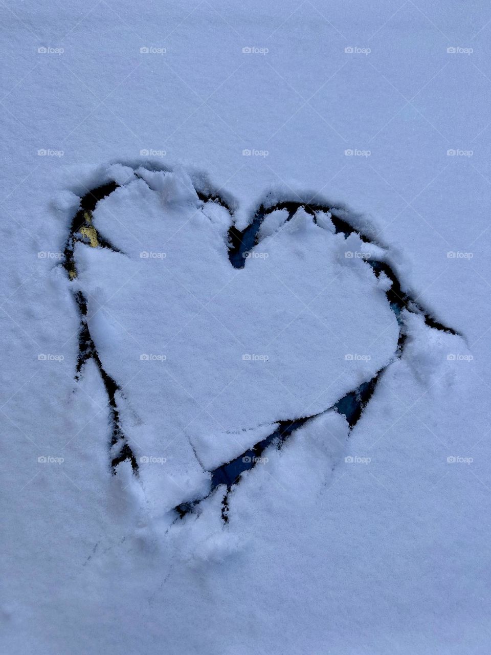 Heart shaped drawn by a person on a snow. 