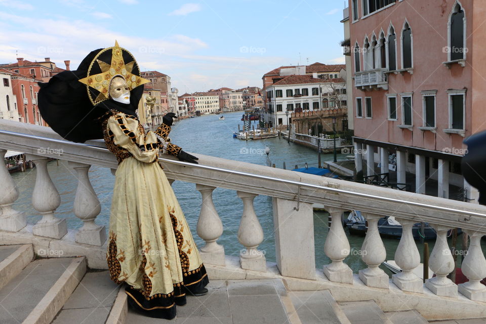 Person in costume standing on bridge near canal