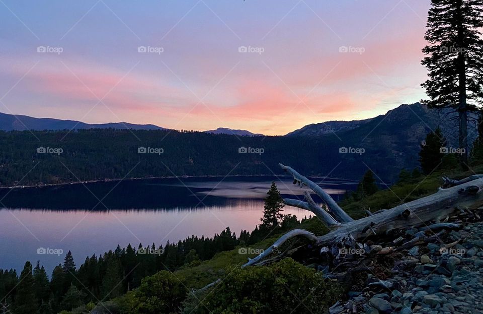 Colorful sunset reflects on a lake with a tree stump in the foreground 