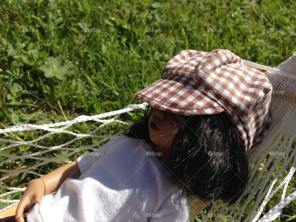 Doll in cap resting in hammock