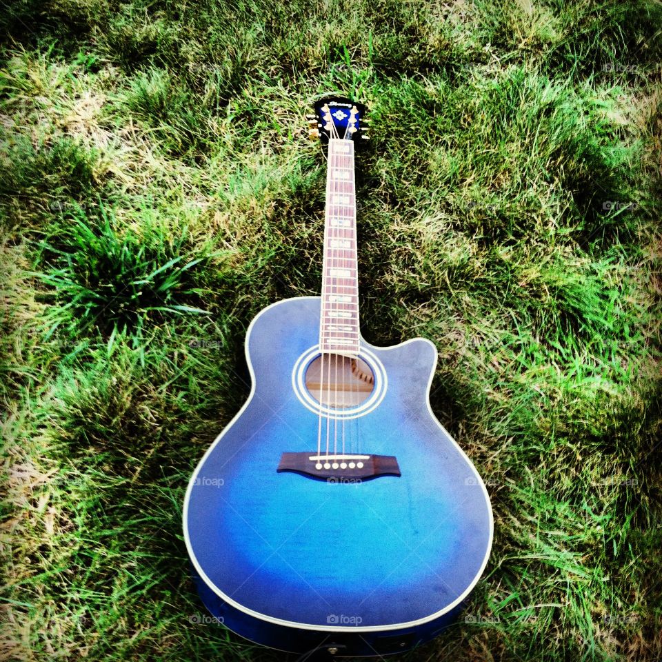 Blue acoustic guitar in grass in the summer
