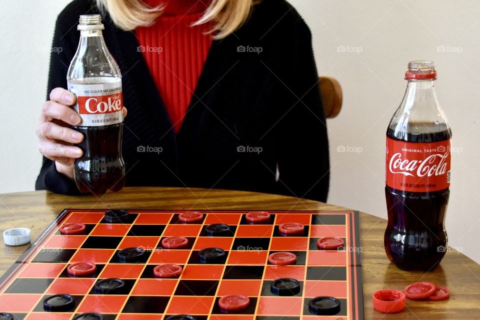 Woman drinking Diet Coke and playing checkers 