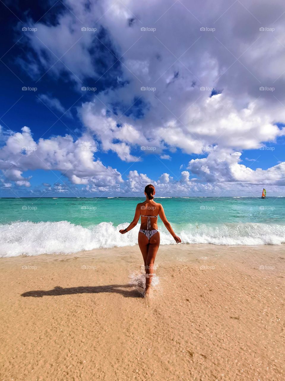 Amazing summer day.
A woman in a bikini running on the sea waves enjoys the beautiful summer weather and warm sea water...