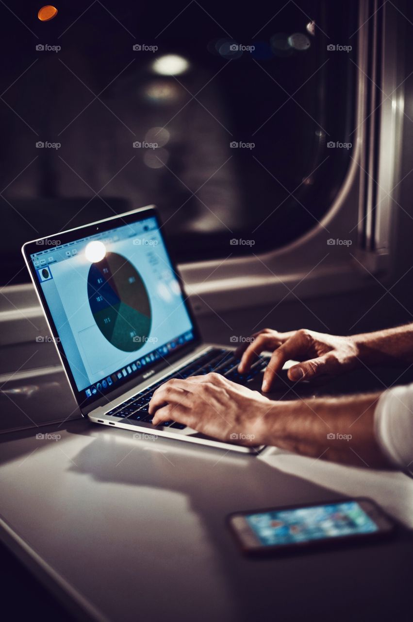 young man working on laptop in a train while traveling