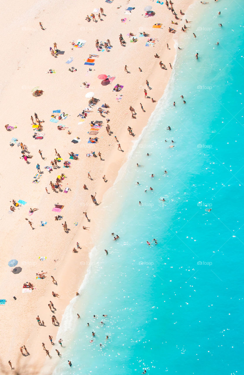People swimming and enjoying the summer at famous shipwreck beach at Zakynthos island in Greece. Aerial picture of people on vacation.