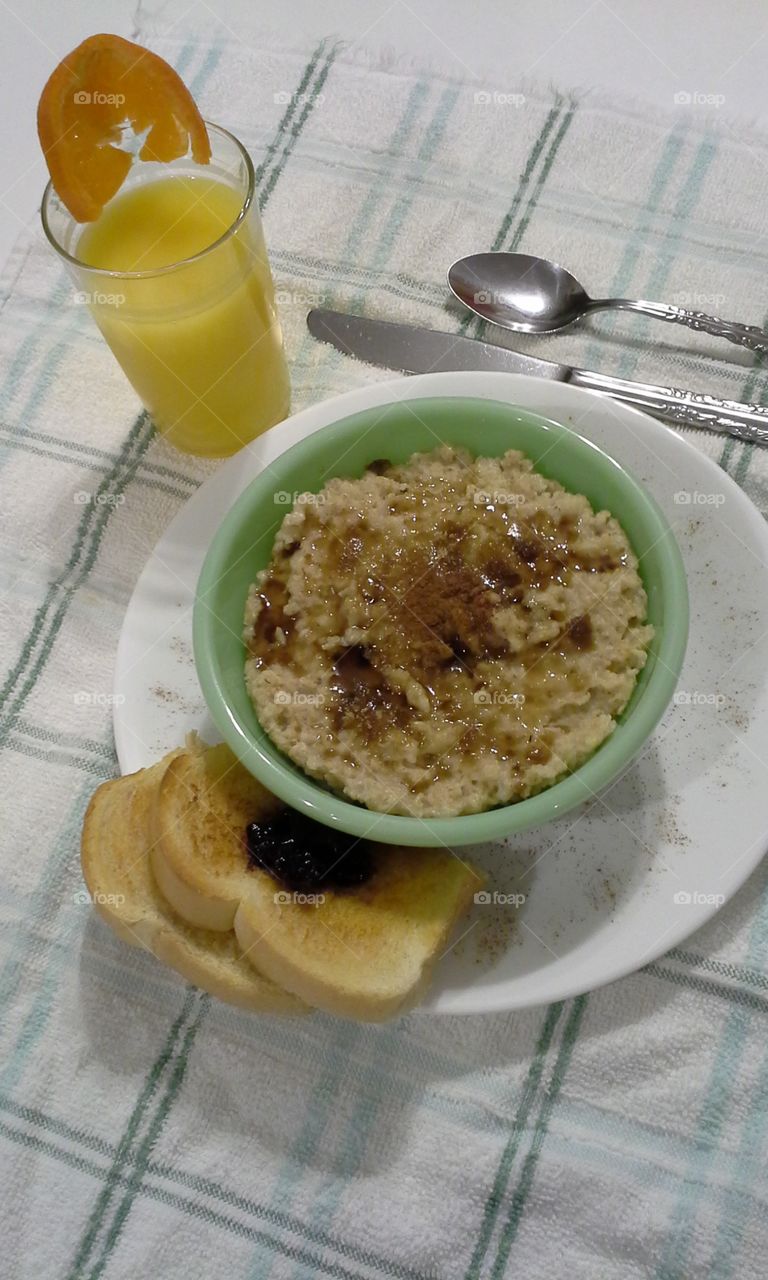 Oatmeal cinnamon sugar in green bowl orange juice toast and homemade blueberry jam