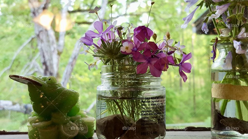 Wildflowers in glass jars on windowsill 