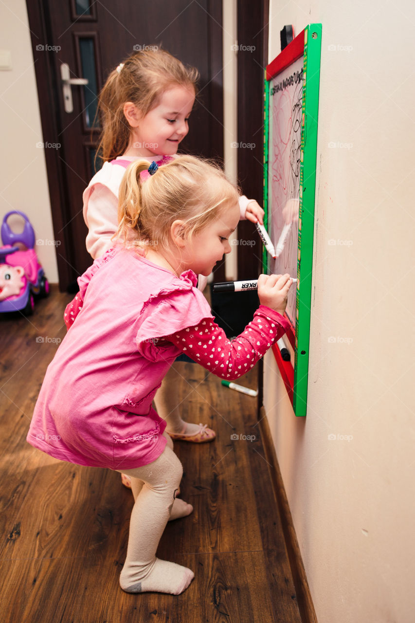 Children drawing a pictures learning a letters playing together using whiteboard and markers