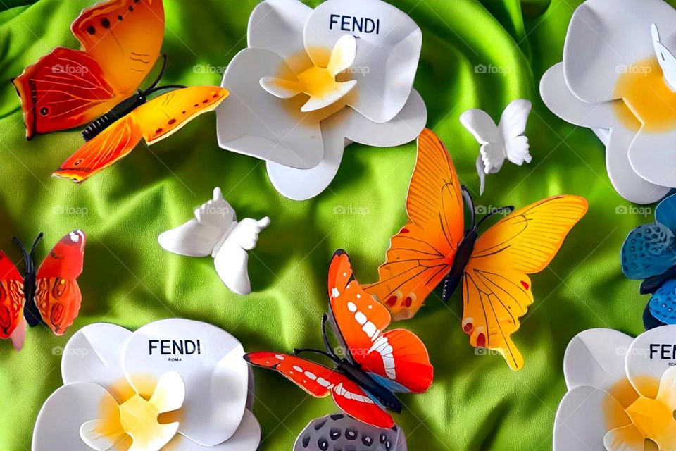 Display of Fendi Orchids and butterflies on green fabric background.
