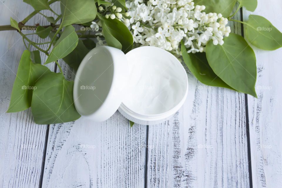 Jars with cosmetic products, beauty cosmetics in a white jar with cream and water with fragrant flowers.