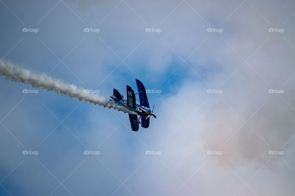 Biplane swoops across the sky with vapor trail