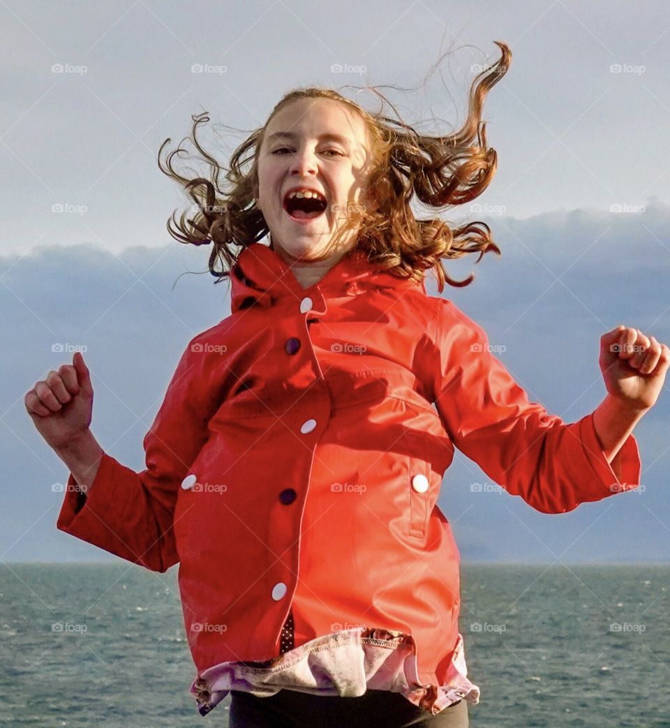 Girl jumps for joy as wind lifts her hair 