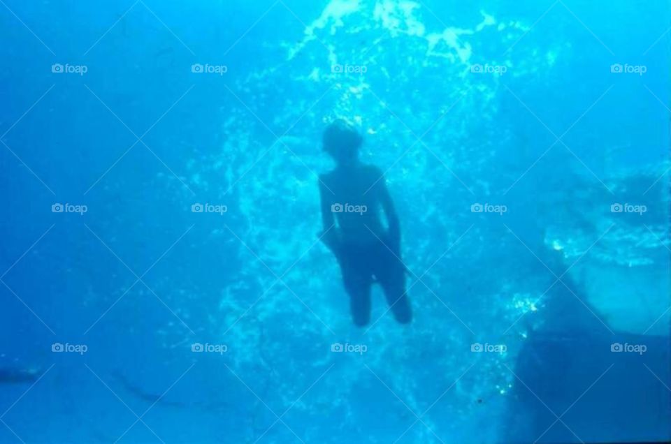 Young boy swimming in blue wat