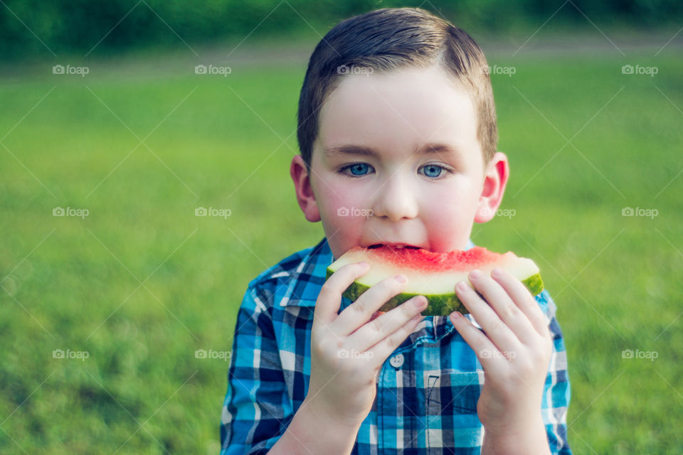 Young Boy Eating Watermelon at the Park on the Grass