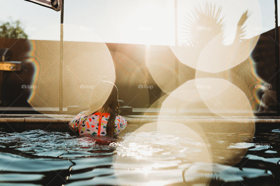 Child in pool outdoors during summer at sunset 
