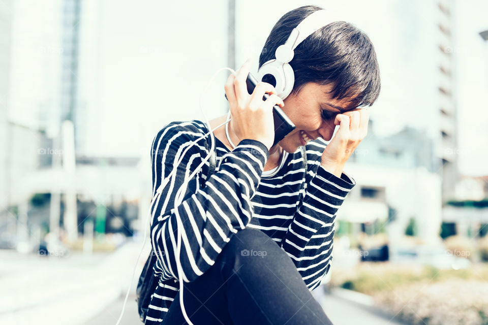 Young woman smiling listening to music with headphones in the city