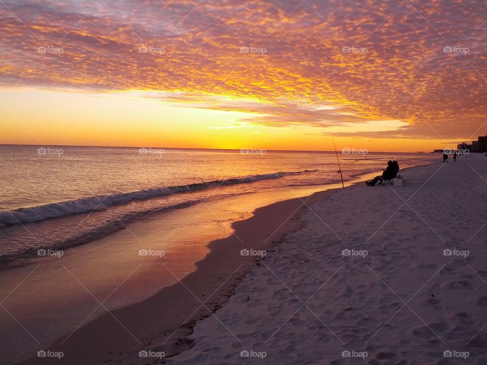 Silhouette of a people with fishing rod at beach during sunset