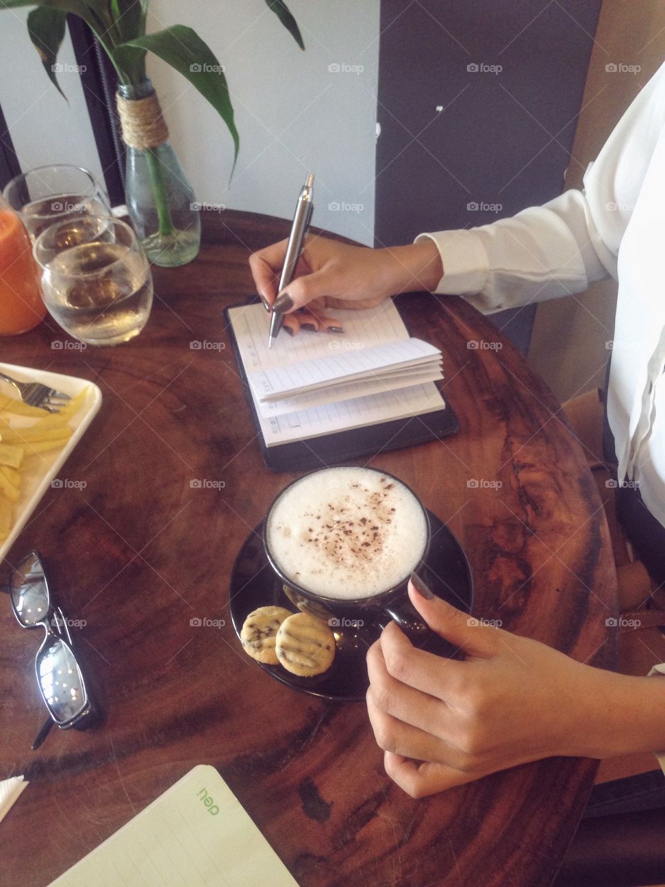 Woman writing in notebook and a cup of coffee 