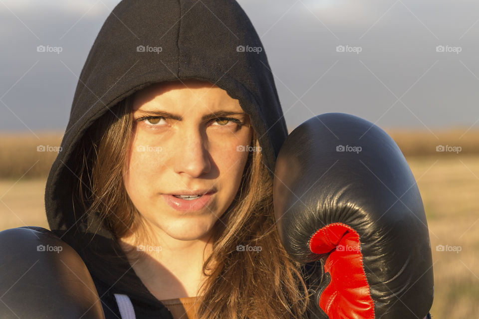 Portrait of female boxer with gloves in hoodie