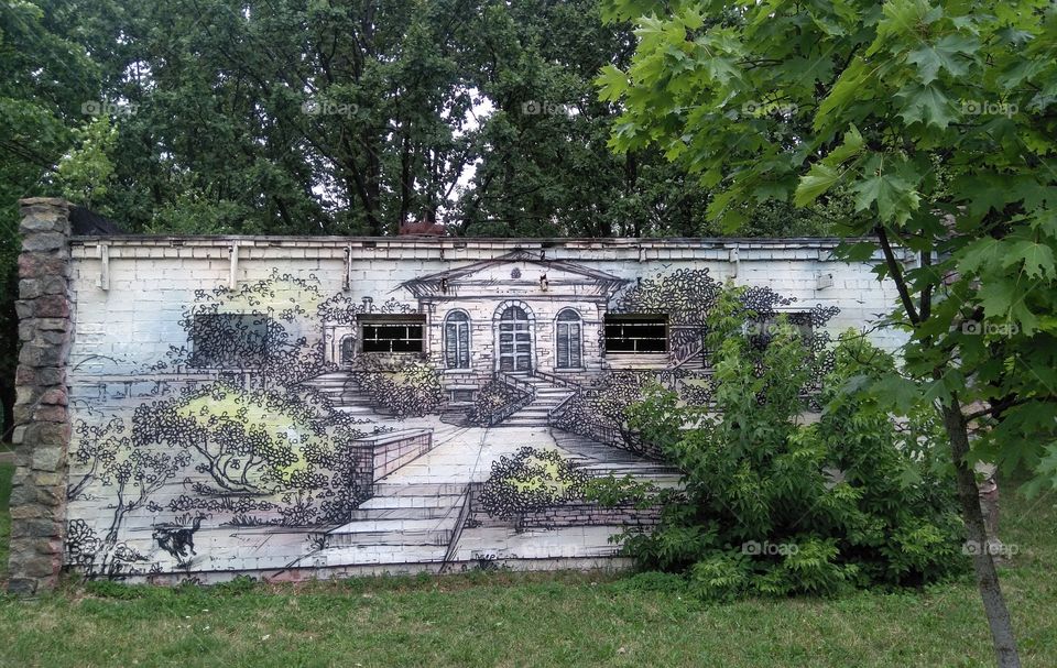 art graffiti house drawing on a wall and green trees in the park summer time