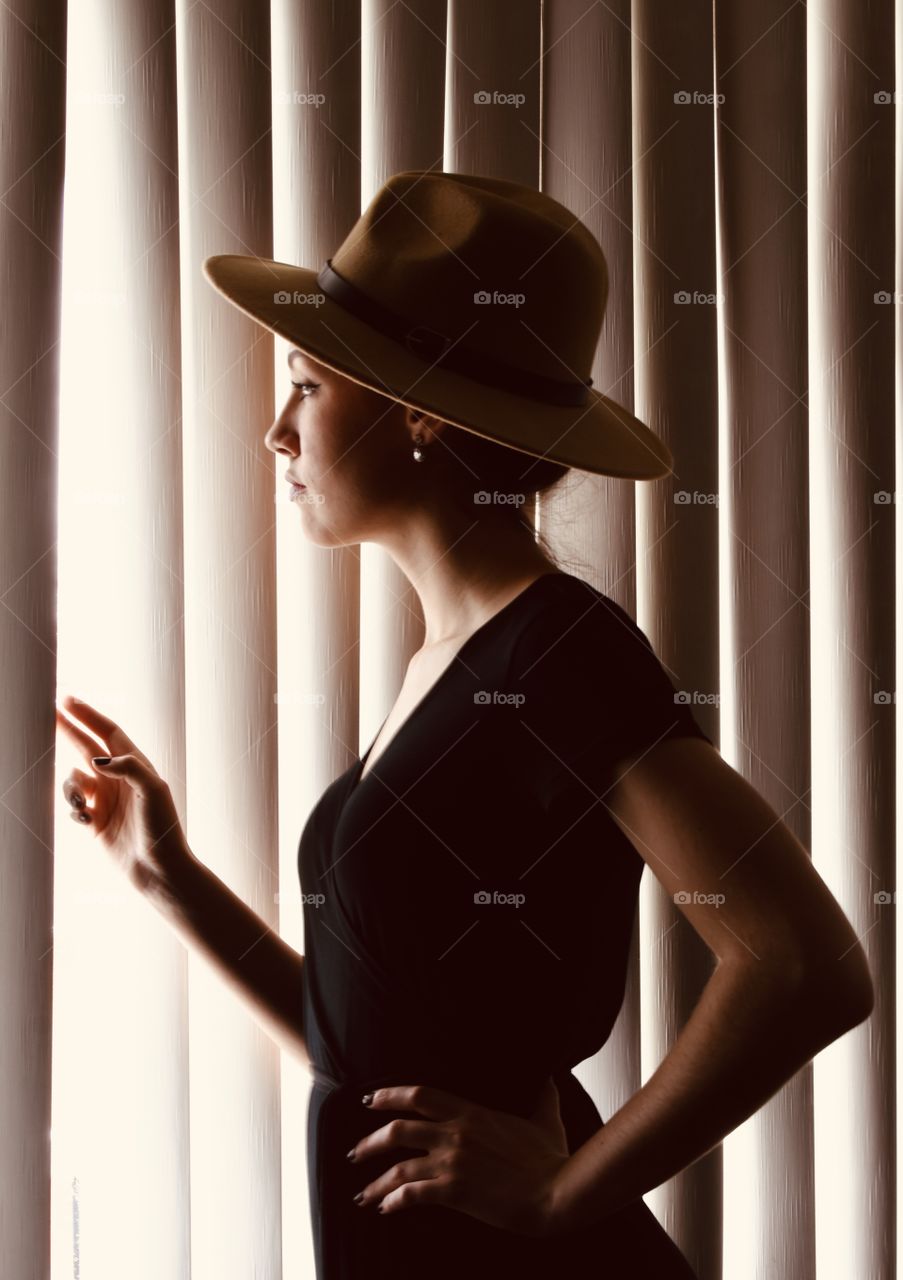 Monochrome woman looking through window blinds 