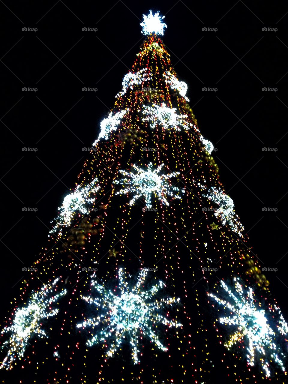 Bright colored illumination on artificial Christmas fir tree in the evening on black sky background in Moscow, Russia