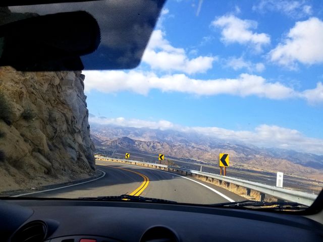 Mazda 2 interior on a roadtrip through mountain pass. 
Left turn arrow street signs on a mountain road.