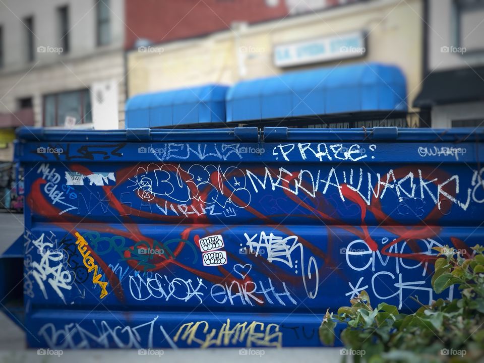 Blue trash bin covered in graffiti outside of a business in Downtown Los Angeles California 
